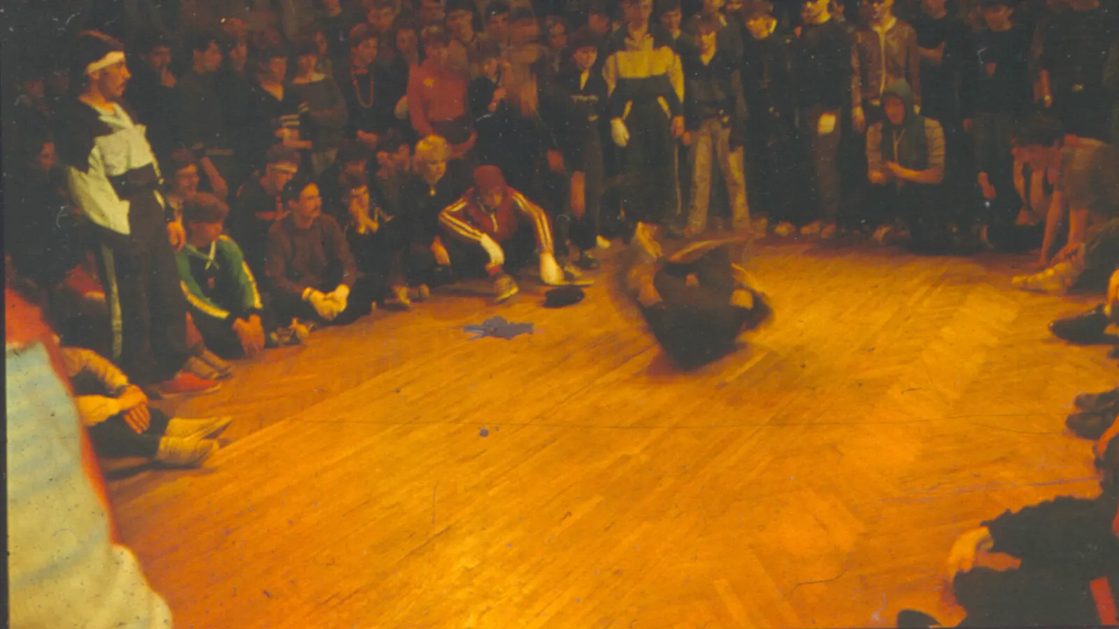 Danseur au sol entouré d'un cercle de spectateurs lors d'une compétition de break-dance à Riga en 1986