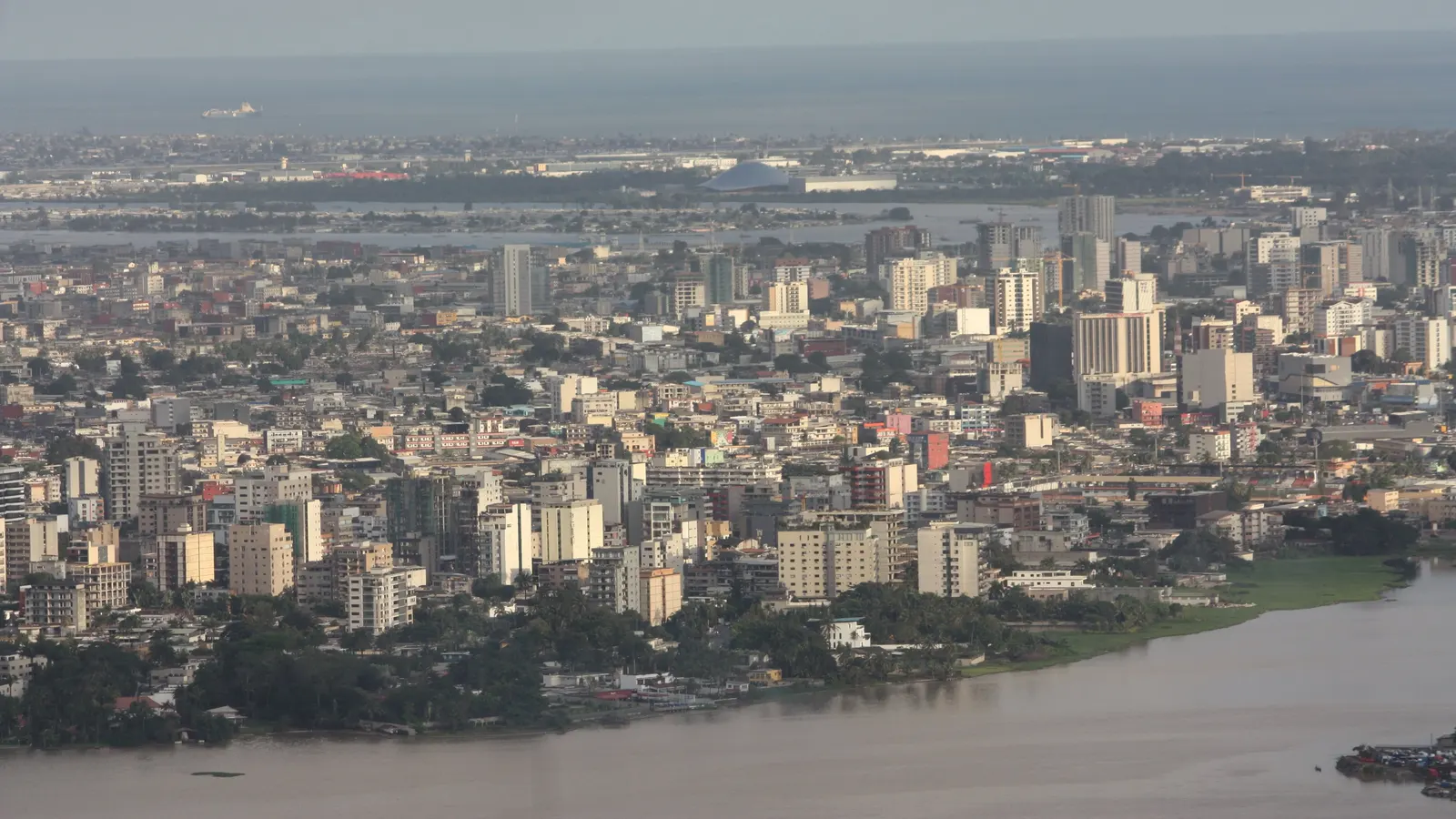 Vue aérienne d'immeubles d'Abidjan au bord de la lagune sous un ciel voilé